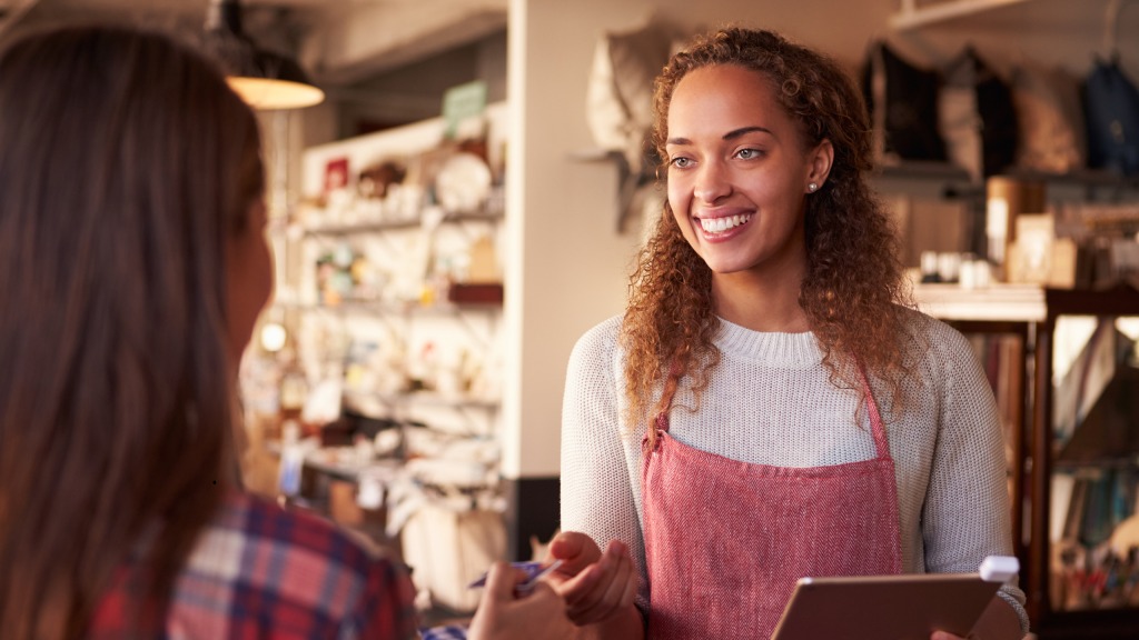 Vendeuse en boutique souriante en interaction avec une cliente – illustration de la formation en situation réelle